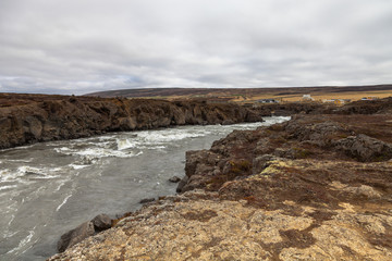 Fototapeta na wymiar Water of the Godafoss Waterfall - beautiful part of stony rocky desert landscape of Iceland. Toned.