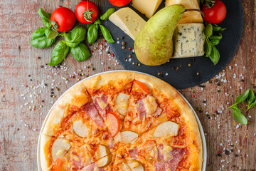 Close up of pizza with pear and ham on a wooden background, top view