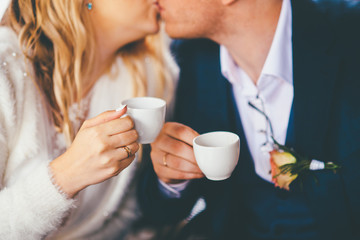 Closeup of couple kissing with cups in hands