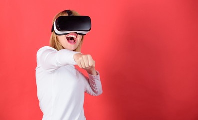 Pretty woman playing game in virtual reality glasses. Portrait of an amazed girl using a virtual reality headset isolated on red background. Woman with virtual reality headset.