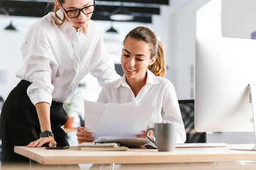 Happy cheerful colleagues business women in office working with documents.