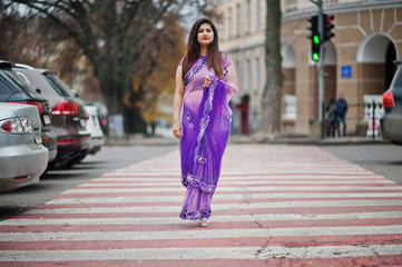 Indian hindu girl at traditional violet saree posed at street , walking at pedestrian crossing.