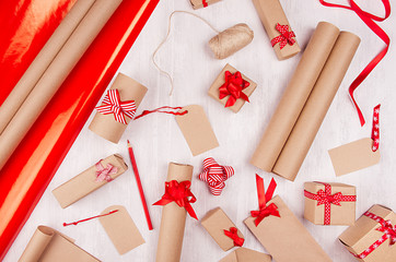 Christmas preparations background - wrapping paper, gift boxes, red ribbon and bows, twine as...