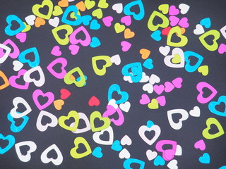 Colorful shiny hearts on a black background. Hearts are arranged randomly.