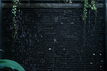 Background and texture of gardening decorations with black tile, waterfall and plant.