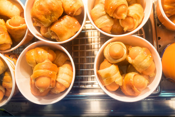 Close up of mini sausage rolls in paper cup.