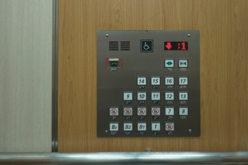Close up of control elevator buttons for disabled human on wooden wallpaper.