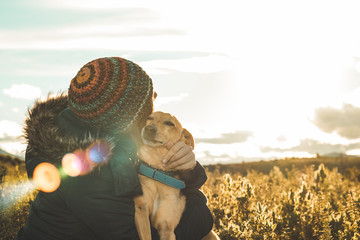 A young woman hugging and kissing her dog at sunset. Concept of love between dog and woman