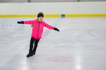 Little girl learning to ice skate. Figure skating school. Young figure skaters practicing at indoor skating rink. © alexngm