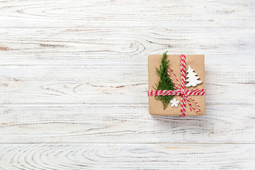 gift box wrapped in recycled paper, with ribbon bow, with christmas decor. Wooden table background, copy space