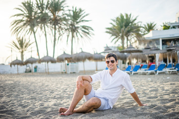 Fototapeta na wymiar Portrait of handsome man sitting relaxed on the beach