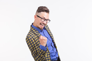 Emotions and people concept - young happy man raised his fists up over the white background with copy space