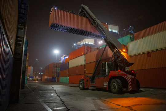 Reach Stacker during operation. Reach-stacker container loader during night work. Industrial port container terminal