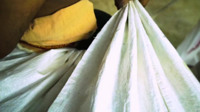 A hand held, panning, close-up shot of an improvised skirt made out raffia bags, being tied up to someone's hips.