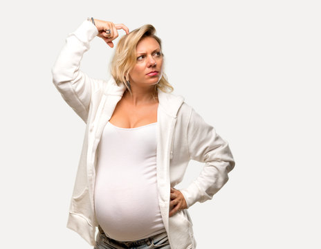 Pregnant blonde woman with white sweatshirt standing and thinking an idea on isolated grey background