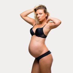 Fototapeta na wymiar Blonde pregnant woman in underwear on isolated grey background