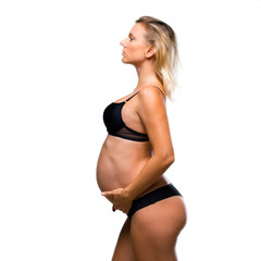 Fototapeta premium Blonde pregnant woman in underwear on isolated white background