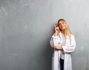 Young doctor woman pointing with the finger a great idea and looking up