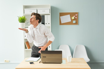 Fun, business and people concept - handsome man blowing at plant in his office, joke, the 1st of april