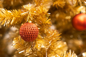 Obraz na płótnie Canvas red glitter christmas light ball on golden christmas tree