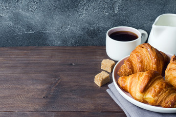 Freshly baked croissants on a plate, dark background, copy space.