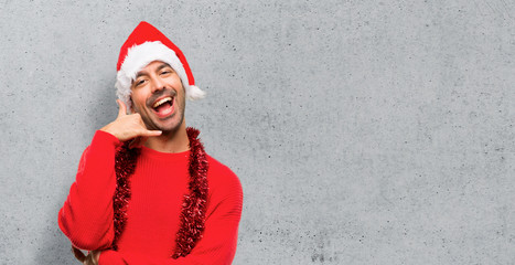 Man with red clothes celebrating the Christmas holidays making phone gesture. Call me back sign on textured background