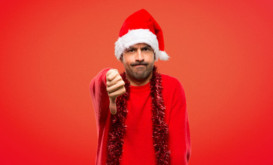 Fototapeta premium Man with red clothes celebrating the Christmas holidays showing thumb down sign with negative expression on red background
