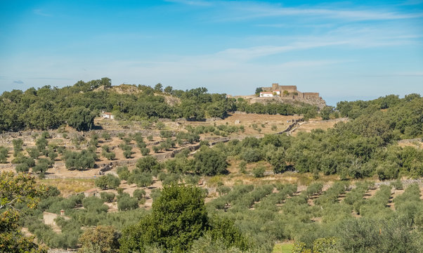 View of the Montanchez Castle with the cultivation area in the foreground