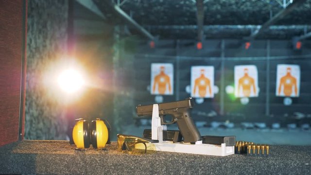 A gun with headphones and glasses on a table. Ammunition, guns, weapons at a fire range.