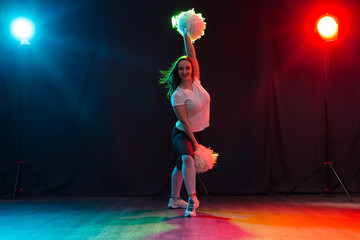 Cheerleading young woman dancing with pom-poms on colourful background © satura_