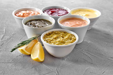 Different tasty sauces in bowls on grey background