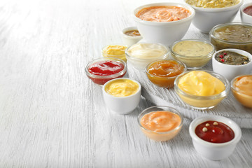 Different tasty sauces in bowls on white wooden table