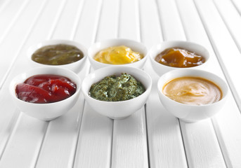 Different tasty sauces in bowls on white wooden table
