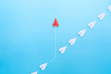 Business concept for innovation and solution with group of white paper plane in one direction and one red paper plane pointing in different way on blue background. - obrazy, fototapety, plakaty