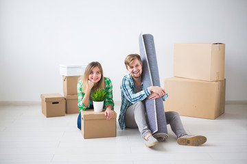 Fototapeta na wymiar Relocation, real estate and moving concept - Young cheerful couple moving into their new home