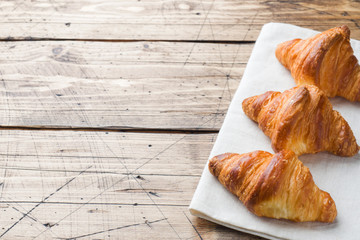 Breakfast croissants on a plate and a Cup of coffee, wooden background, copy space.