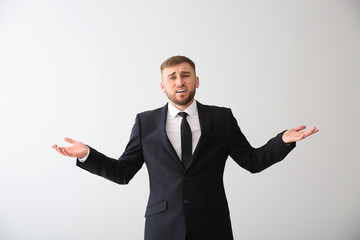 Emotional young businessman after making mistake on white background