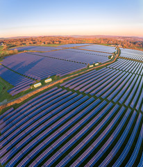 Aerial drone view of solar panels at a solar energy generation farm at Sunset in South Wales, UK