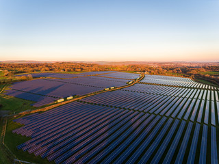 Aerial drone view of solar panels at a solar energy generation farm at Sunset in South Wales, UK