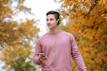 Obraz premium Young man listening to music in autumn park