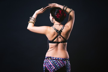 Women performs belly dance in ethnic dress on black background