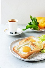 American breakfast on a plate with fried eggs in toast, with tomatoes, fresh daikon, carrots, arugula and espresso. Fried egg for traditional breakfast close up shoot