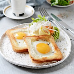 American breakfast on a plate with fried eggs in toast, with tomatoes, fresh daikon, carrots, arugula and espresso. Fried egg for traditional breakfast close up shoot