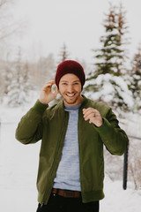 Young Trendy Man in Green Bomber Jacket Enjoying the Winter Snow on a Small Bridge in Colorado