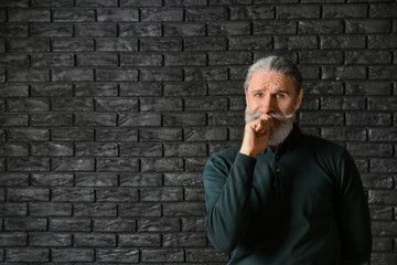 Emotional senior man after making mistake on dark background