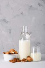 Almond milk in glass and bottle with whole organic almonds on table