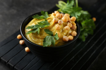 Bowl with tasty hummus on wooden board