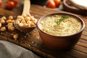 Bowl with tasty hummus on wooden board, closeup