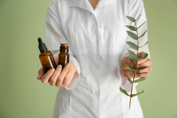 Pharmacologist with bottles of eucalyptus essential oil on color background © Pixel-Shot
