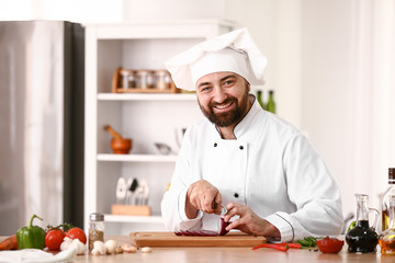 Male chef cutting onion in kitchen
